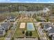High-angle aerial view features neighborhood tennis and sand volleyball courts surrounded by trees and homes at 115 White Lake Ct, Cary, NC 27519