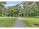 Beautiful backyard view with a charming walking path and tree lined water feature in the distance at 115 White Lake Ct, Cary, NC 27519
