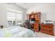 Well-lit bedroom featuring a comfortable bed, desk, and a view of the outdoor area at 122 Tall Timber Dr, Gibsonville, NC 27249