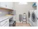 Well-equipped laundry room featuring white cabinets, gray subway tile backsplash, and modern washer and dryer at 122 Tall Timber Dr, Gibsonville, NC 27249