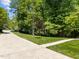 Lush front yard with mature trees and green grass, showcasing landscaping at 12200 Glenlivet Way, Raleigh, NC 27613