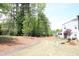 View of a backyard with a line of trees, a walking path and a glimpse of the house at 123 Hunston Dr, Holly Springs, NC 27540