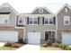 Exterior view of three townhomes with stone facades, garages and nicely landscaped yards at 123 Hunston Dr, Holly Springs, NC 27540