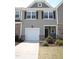 View of a townhome with a one car garage, stone facade, and well maintained landscaping at 123 Hunston Dr, Holly Springs, NC 27540