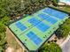 Aerial shot of tennis and basketball courts, lit for evening play, surrounded by greenery at 1241 Dalgarven Dr, Apex, NC 27502