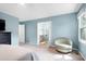 A blue bedroom with carpet, a ceiling fan, two windows, and a chair at 1321 Bloomingdale Dr, Cary, NC 27511