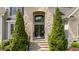 Stunning front entrance with double doors, stone archway, large transom window, and evergreen shrubbery at 14013 Wallberman Dr, Wake Forest, NC 27587