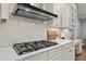 Close up of kitchen featuring a stainless steel range hood, gas cooktop, quartz countertops, and herringbone backsplash at 14013 Wallberman Dr, Wake Forest, NC 27587