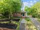 Charming brick home with a craftsman-style porch and modern cable railing, enhanced by lush landscaping and a stone pathway at 1402 W Lakewood Ave, Durham, NC 27707