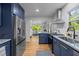 Open kitchen with stainless appliances, navy cabinets, marble countertops, and bright eat-in area at 1402 W Lakewood Ave, Durham, NC 27707
