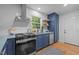 Well-appointed kitchen features stainless appliances, including a range with stainless hood, and navy cabinets at 1402 W Lakewood Ave, Durham, NC 27707