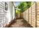 Side yard featuring a gravel pathway with newly constructed wood fence and side wall of the house with visible brick foundation at 1402 W Lakewood Ave, Durham, NC 27707