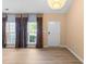 Open-concept living room featuring wood flooring, large windows, and a white entry door at 141 Hilda Grace Ln, Cary, NC 27519