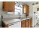 Functional kitchen sink area with wood cabinets, window with floral valance, and view to laundry room with washer/dryer at 141 Montesino Dr, Raleigh, NC 27603