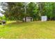 Spacious backyard with a storage container, shed, mature trees, and lush green grass, providing a private retreat at 149 Baldwin Dr, Durham, NC 27712