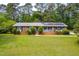 Charming brick home featuring solar panels, manicured bushes, and a well-maintained lawn at 149 Baldwin Dr, Durham, NC 27712
