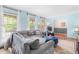 Cozy living room featuring a plush grey sofa, ottoman, three windows, and hardwood flooring at 149 Baldwin Dr, Durham, NC 27712