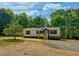 A single-story home nestled among trees with a nice front yard and gravel driveway at 1622 Julian Oakley Rd, Rougemont, NC 27572