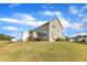 Expansive backyard view showcasing the home's siding, screened porch, and grassy lawn under a bright sky at 1811 Sandoval Dr, Durham, NC 27703