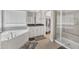 Bathroom featuring a large soaking tub, shower, dual mirrors, and natural light from the window at 1811 Sandoval Dr, Durham, NC 27703