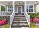 Inviting front porch with stone stairs, white railings, and colorful landscaping at 1811 Sandoval Dr, Durham, NC 27703