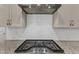 Close-up on gas range stove and hood fan with white tile backsplash and granite countertops at 1811 Sandoval Dr, Durham, NC 27703
