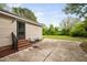 Backyard patio with chairs, brick steps, and green grassy area, surrounded by trees and blue skies at 2005 Chalybeate Springs Rd, Fuquay Varina, NC 27526
