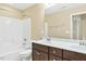 Bathroom featuring dual sinks, white tiled shower-tub, and wooden cabinets at 225 Gulley Glen Dr, Garner, NC 27529