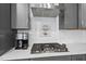 Modern kitchen with gray cabinets, stainless steel range hood, gas cooktop, and stylish backsplash at 2323 Big Sky Ln, Raleigh, NC 27615
