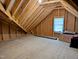 Spacious attic area with plywood flooring, a window, and exposed wood framing at 2472 Patriot Bluffs Dr, Fuquay Varina, NC 27526