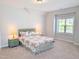 Bright bedroom features a floral patterned queen bed, two side tables, and a window at 2472 Patriot Bluffs Dr, Fuquay Varina, NC 27526