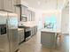Bright kitchen features stainless steel appliances, gray cabinetry, granite countertops, and a kitchen island at 2472 Patriot Bluffs Dr, Fuquay Varina, NC 27526