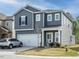A charming two-story home with gray siding and a two-car garage, complemented by a well-kept lawn at 253 Sweet Olive St, Clayton, NC 27527