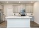 Bright kitchen featuring an island, gray cabinets, stainless steel appliances, and modern finishes at 253 Sweet Olive St, Clayton, NC 27527