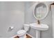 Cozy powder room featuring a pedestal sink, round mirror, and tile flooring at 2639 Oleander Dr, Durham, NC 27703