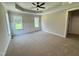 Spacious bedroom featuring tray ceilings, plush carpet, and abundant natural light from windows at 27 Batten Hill Ln, Selma, NC 27576