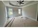 Spacious main bedroom featuring a tray ceiling, ceiling fan, and large windows for natural light at 27 Batten Hill Ln, Selma, NC 27576