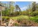 Lush backyard with mature trees, green grass, and garden areas creating a private outdoor retreat at 2925 Ericka Dr, Hillsborough, NC 27278