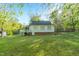 View of the backyard of a cottage featuring a deck and ample green space, partially enclosed by a chain-link fence at 2925 Ericka Dr, Hillsborough, NC 27278