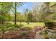 Expansive backyard featuring a brick pathway, lush greenery, and mature trees creating a private oasis at 2925 Ericka Dr, Hillsborough, NC 27278