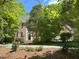 View of the brick home with mature trees and landscaping from the driveway at 3316 Belspring Ln, Raleigh, NC 27612