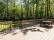 Wooden deck with a table and seating overlooking the landscaped backyard with mature trees at 3332 Langston Cir, Apex, NC 27539