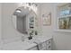 Bright bathroom featuring white vanity with marble countertop, round mirror, and window at 3408 Brentwood Rd, Raleigh, NC 27604