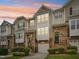 Charming multi-level townhouse featuring stone accents, a garage, and lush landscaping against a vibrant sunset sky at 5026 Celtic Ct, Raleigh, NC 27612