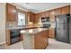 Modern kitchen featuring wooden cabinets, tiled backsplash, and island, with black appliances at 503 Bellefont Ct, Knightdale, NC 27545