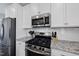 Modern kitchen featuring stainless steel appliances, granite countertops, and white cabinetry at 509 National Dr, Clayton, NC 27520