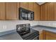 Close-up of the kitchen's black oven and microwave set among the ample wood cabinets at 5609 Severn Grove Dr, Durham, NC 27703