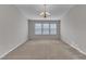Bright, carpeted living room featuring a modern chandelier and a wall of windows at 5609 Severn Grove Dr, Durham, NC 27703