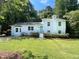 Charming white two-story home with a teal front door, mature landscaping, and a well-maintained lawn at 5817 Wintergreen Dr, Raleigh, NC 27609