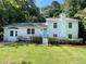 Charming white two-story home with a teal front door, mature landscaping, and a well-maintained lawn at 5817 Wintergreen Dr, Raleigh, NC 27609